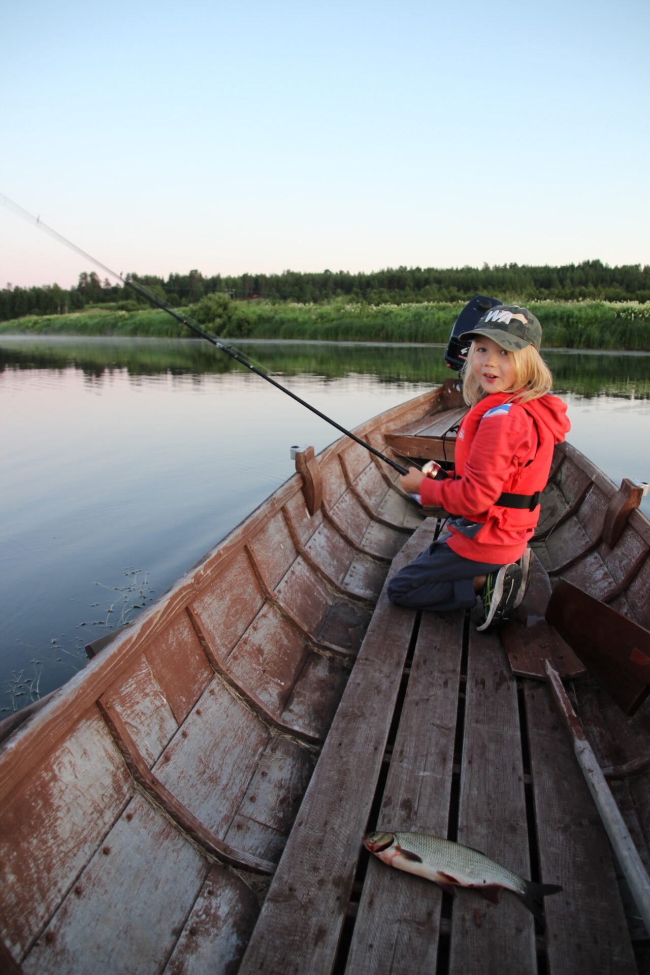Lapsi kalastaa jokiveneestä Nivankylässä (c) Piia Juntunen-Laakso 2020